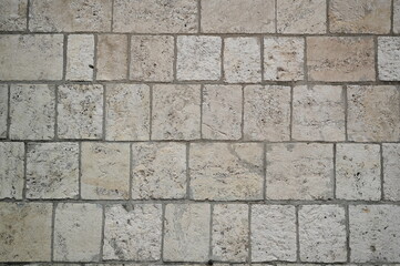 grey stone pavement with rectangular cobblestones in light gray and beige tones. Geometric street texture background
