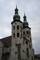 Fototapeta premium Historic tower with spire against dramatic cloudy sky. Old European architecture with gothic details and red brick wall