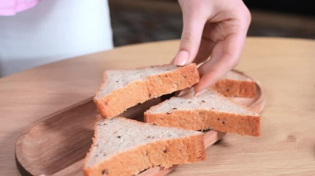 Hand reaching for a slice of fresh multigrain bread on wooden board, showcasing healthy food, natural texture, and simple homemade nutrition in a cozy setting