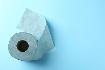 Color toilet paper roll on light blue background, top view. Space for text