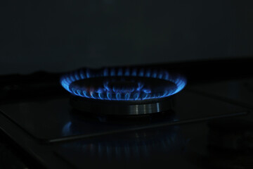 Gas burner with blue flame on stove, closeup