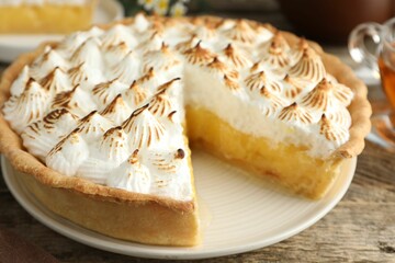 Delicious pie with browned meringue on wooden table, closeup