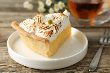 Piece of delicious pie with browned meringue and fork on wooden table, closeup
