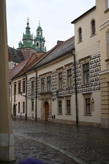 Obraz premium Historic European street with old buildings and church tower. Narrow cobblestone alley with traditional architecture, ideal for travel, tourism, and cultural heritage themes.