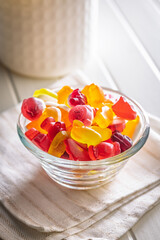 The colorful jelly candies in bowl on white table.
