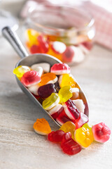 The colorful jelly candies in scoop on white table.