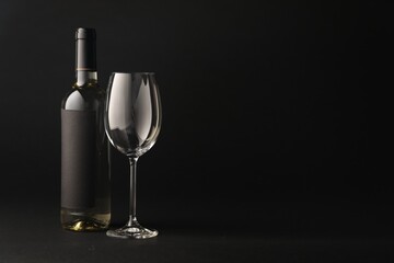 Bottle of wine and glass on black background, space for text