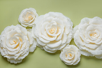 Beautiful white paper flowers on light green background, flat lay