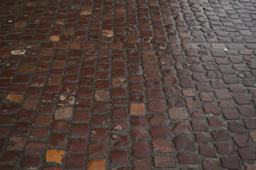 Modern stone pavement texture with square tiles in neutral gray and beige tones. Urban sidewalk background for architecture, design, and construction projects. Clean geometric pattern of paving slabs.