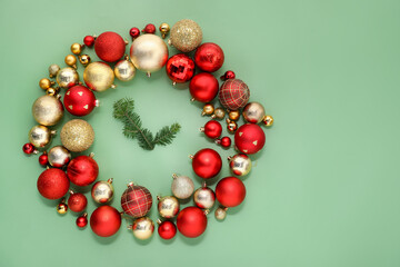 Clock made with Christmas decor and fir tree branches on green background, flat lay. Space for text