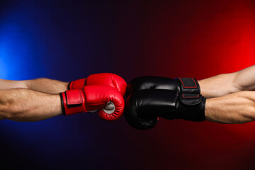 Men with boxing gloves fighting on dark background in neon lights, closeup