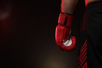Man in boxing glove on dark background, closeup. Space for text