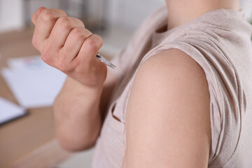 Man making insulin injection into his arm indoors, closeup. Diabetes