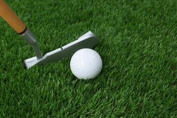 Golf ball and club on green grass, closeup