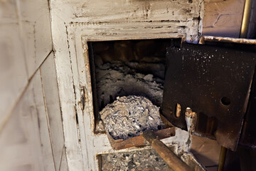 Cleaning a village stove. A man uses a scoop to remove ash from the stove.