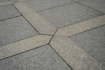 Stone pavement with geometric pattern of gray and beige tiles. Urban sidewalk texture with...