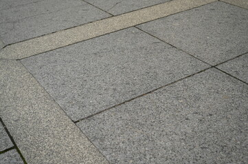 Fototapeta premium Stone pavement with geometric pattern of gray and beige tiles. Urban sidewalk texture with decorative lines