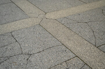 Stone pavement with geometric pattern of gray and beige tiles. Urban sidewalk texture with decorative lines