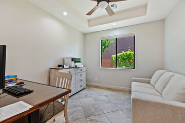 A cozy living room with a couch, desk, and ceiling fan