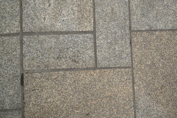 Fototapeta premium Granite pavement texture with geometric stone pattern. Urban background of grey and beige paving blocks — natural stone surface for architecture, design, and construction concepts.