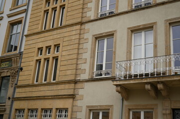 Classic European building facade with tall windows and decorative balcony railings. Beige stone architecture in Luxembourg city — elegant example of historical urban design.