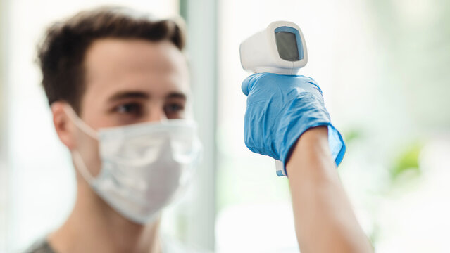 Manager checking body temperature of man with contactless thermometer, close up - Powered by Adobe