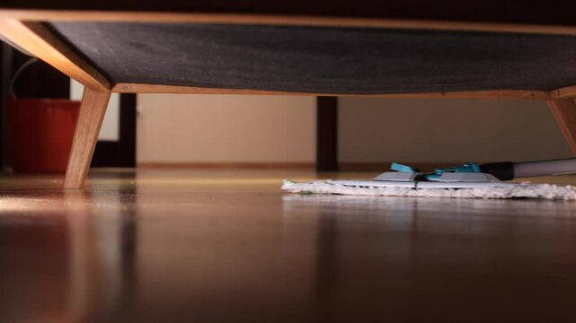 Cleaning hardwood floor under bed with mop