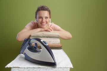 Relaxed woman with iron on olive green backdrop
