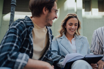 University students reading notes and smiling together outdoors