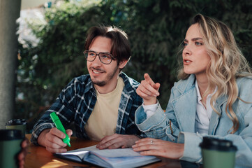 Students discussing project outdoors and taking notes