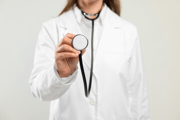 Doctor with stethoscope on light background, closeup