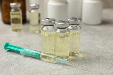 Hepatitis vaccine in glass vials and syringe on grey table, closeup