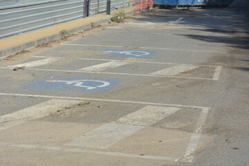 Parking area showing faded markings and debris near construction site on a sunny day