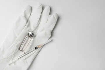 Hepatitis vaccine in glass vial, syringe and medical gloves on white background, top view. Space...