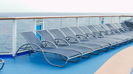 A serene view of blue deck chairs perfectly arranged in neat rows on a luxurious cruise ship deck.