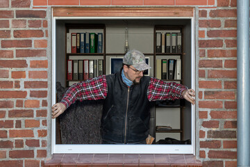 Carpenter installing new energy-efficient window in brick house renovation.