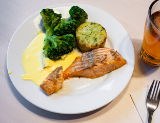 Baked salmon fillet served with broccoli, baked potato and sauce