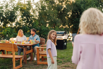 Happy girl smiling at family gathering in backyard garden during summer evening barbecue party