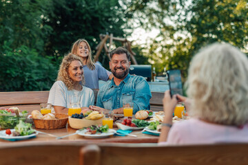 Grandmother taking photo of family enjoying outdoor meal