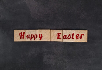 Fototapeta premium Easter cookies with red marmalade filling in the shape of Happy Easter words. Dark gray background. Top view 