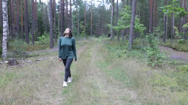 woman walking in the forest in summer in a green sweater