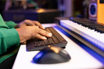 Male artist editing his recorded music in post production, working with a professional software on...