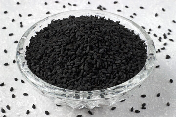 black cumin Nigella sativa in glass bowl on grey kitchen table
