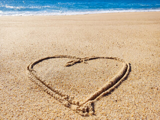 Heart drawn in sand at oceans edge. Represents love, romance, or vacation. Evokes feelings of happiness, relaxation, and connection. Ideal for travel, romance, or wellness themes.