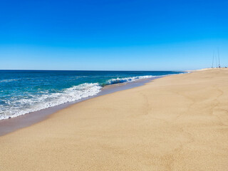 Serene coastal view with pristine beach meeting the azure ocean under a clear blue sky. Perfect for travel, relaxation, or inspirational themes.