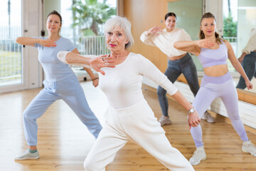 Obraz premium Dynamic elderly woman attendee of dance studio doing aerobics during training session. Women training dance in hall