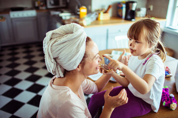 Single mother having breakfast with her young daughter in the kitchen