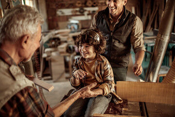 Three male generations working together on a woodworking project in family workshop