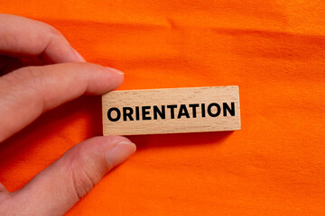 Orientation message written on wooden block on orange background. Conceptual orientation symbol. Copy space.
