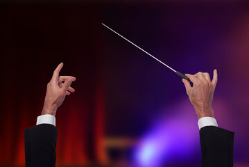 Conductor with baton in concert hall, closeup